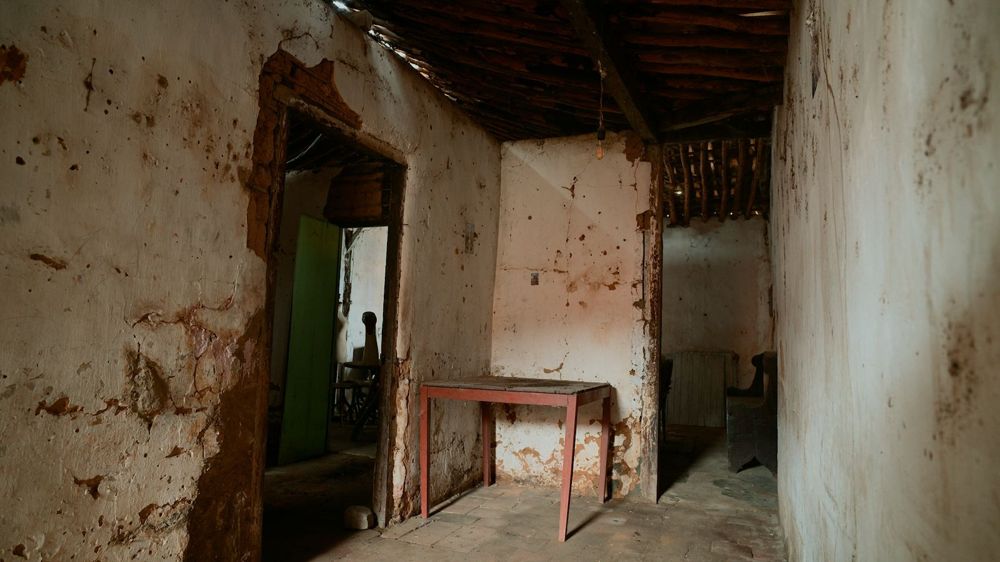 Interior da Casa 1940: cômodo com paredes descascadas e telhado de madeira