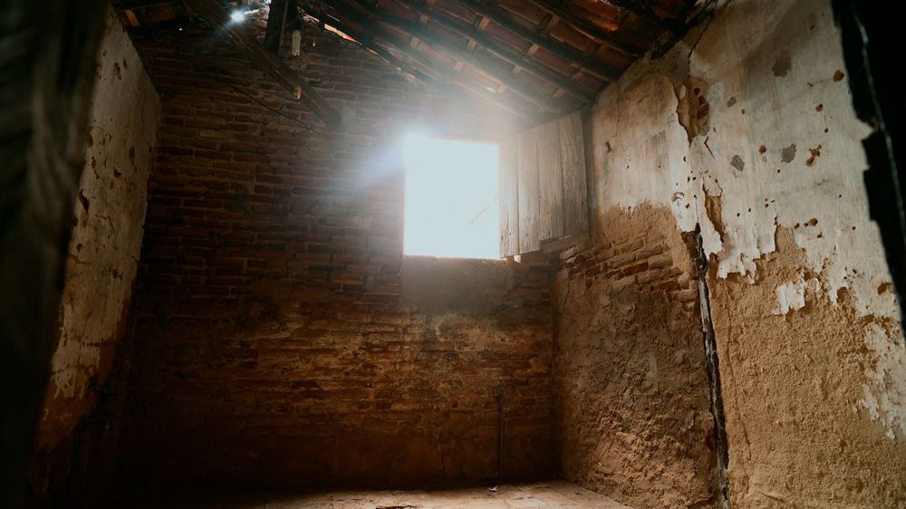 Cômodo com parede de tijolo aparente e luz entrando pela janela
