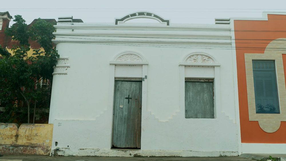 Fachada da Casa 1940 no estado atual, com porta de madeira desbotada